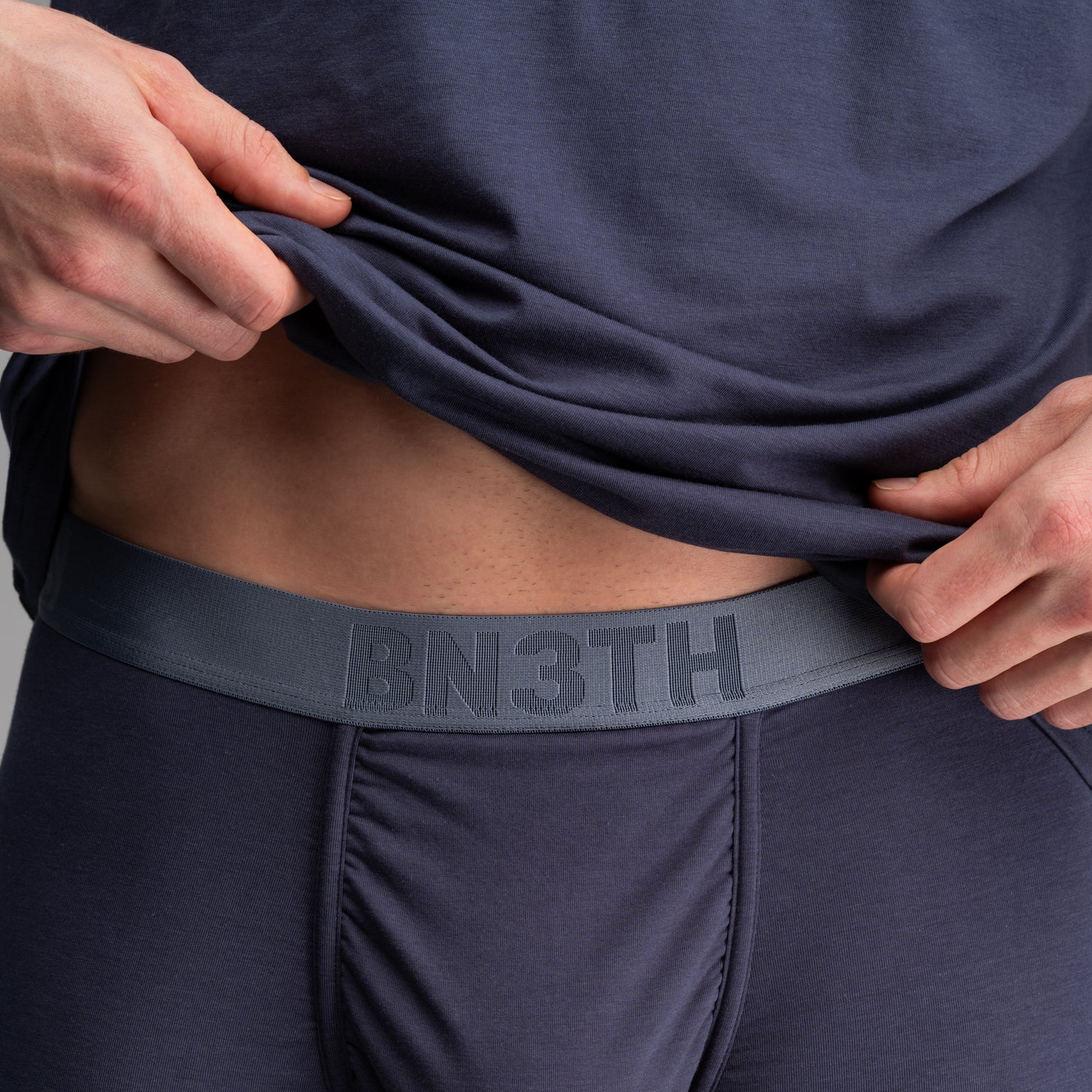 Man wearing navy blue underwear and t-shirt on a gray background. Essentials Boxer Brief: Midnight Navy

