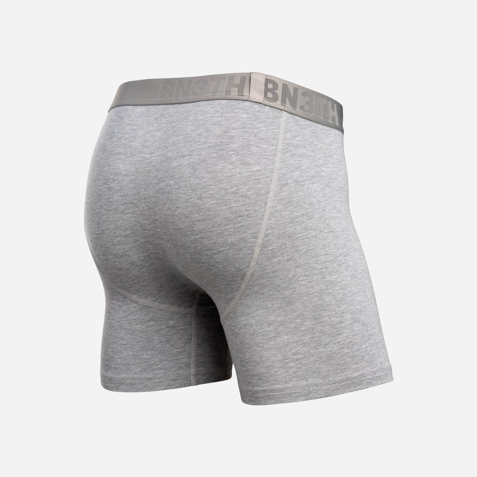 Gray heather boxer briefs shown from a rear three-quarter view, featuring a wide gray elastic waistband with the brand name 'BN3TH' printed in gray. Essentials Boxer Brief: Heather Gray